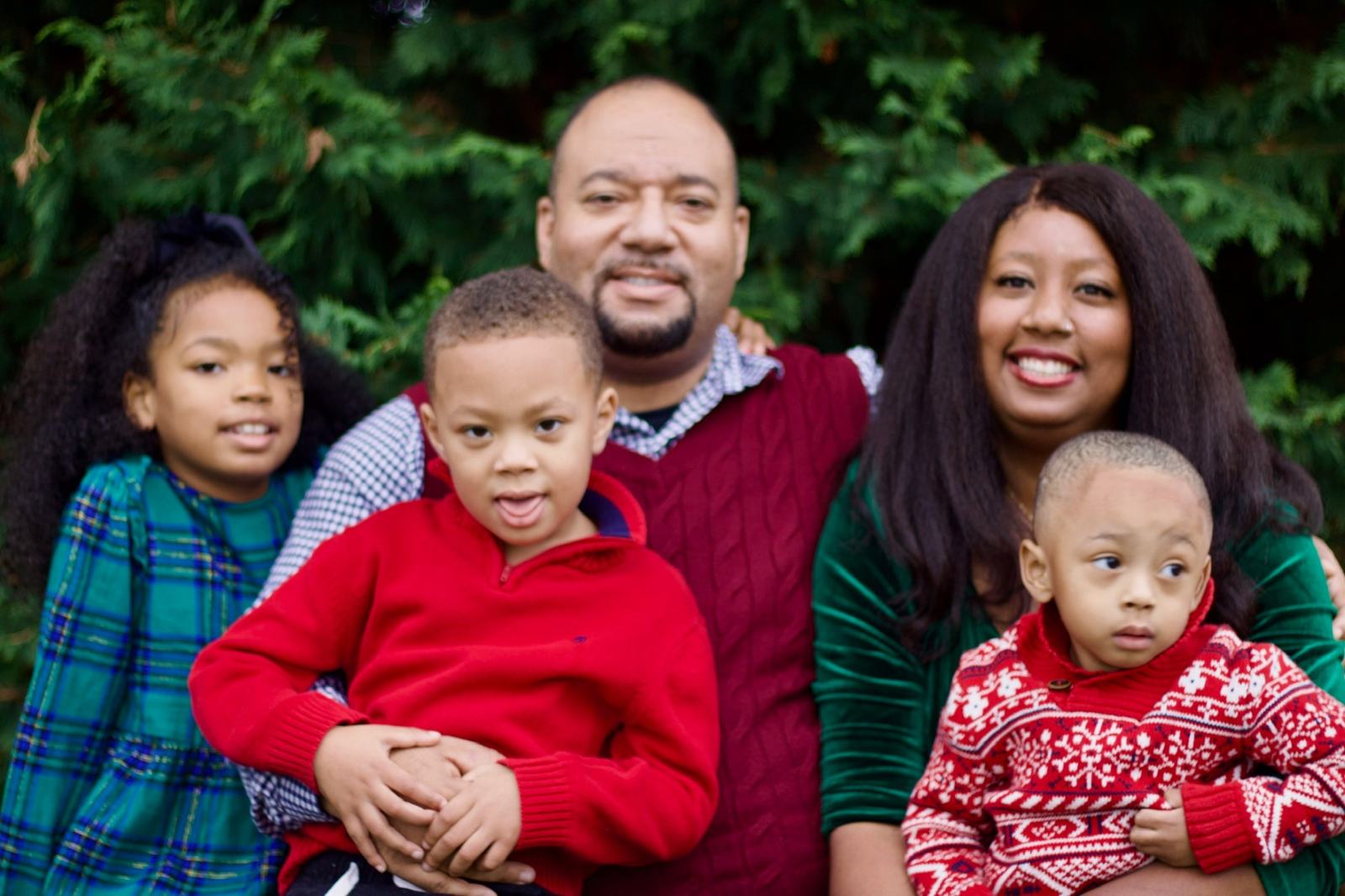 Shondra and Michael Bryan with their three children, outdoors in front of evergreen trees